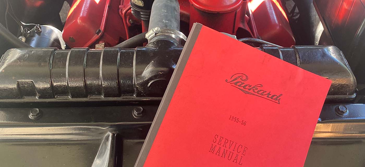 The 1955-56 Packard service manual resting against the engine, in the engine bay.